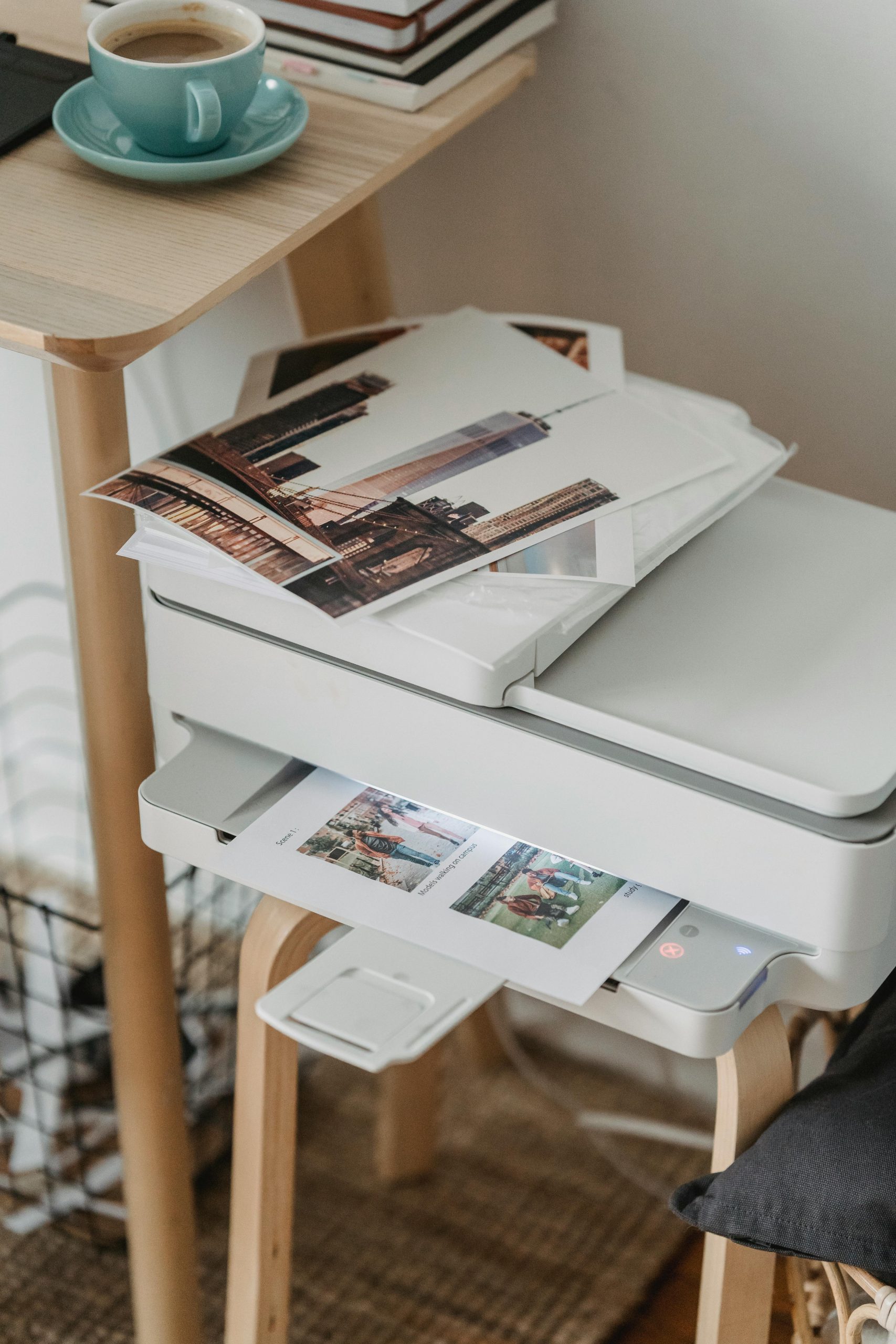 pexels-photo-7014415-7014415 A cozy home office corner with a printer, coffee cup, and printed photos on a wooden table.